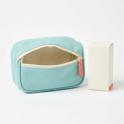 Aqua organizer pouch with ivory zipper and coral pull beside ivory carton on white