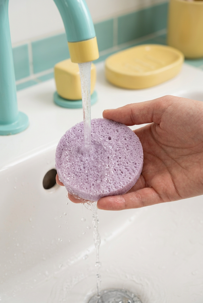 Lavender facial sponge being rinsed with water