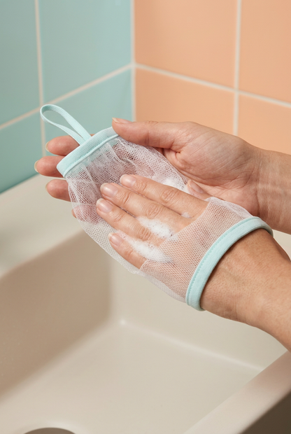 Hands preparing cleanser lather with a mesh foaming net
