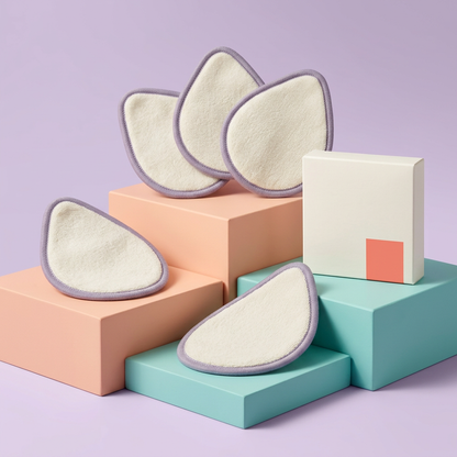 Five ivory teardrop makeup remover pads with lavender edging on colorful podiums
